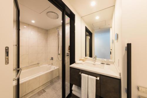 a bathroom with a tub and a sink and a bath tub at Hotel Metropolitan Kawasaki in Kawasaki