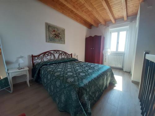 Schlafzimmer mit einem Bett mit grüner Tagesdecke in der Unterkunft La Petite Maison in Gargnano