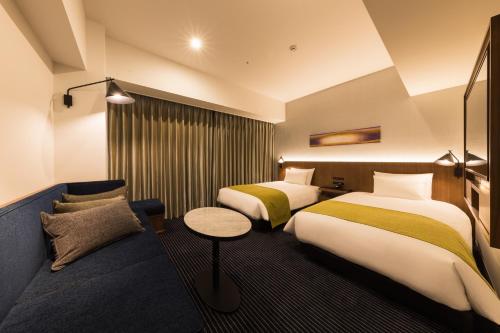 a hotel room with two beds and a couch at Hotel Metropolitan Kawasaki in Kawasaki