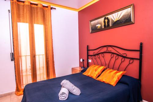 a bedroom with a bed and a red wall at Apartaments Yaco in Lloret de Mar