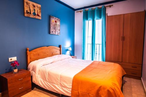 a bedroom with a bed and a blue wall at Apartaments Yaco in Lloret de Mar