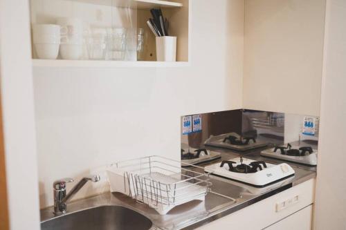 a kitchen counter with a sink and a stove at KYOBASHI BASE in Osaka