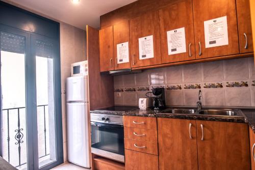 a kitchen with wooden cabinets and a sink and a refrigerator at Apartaments Yaco in Lloret de Mar