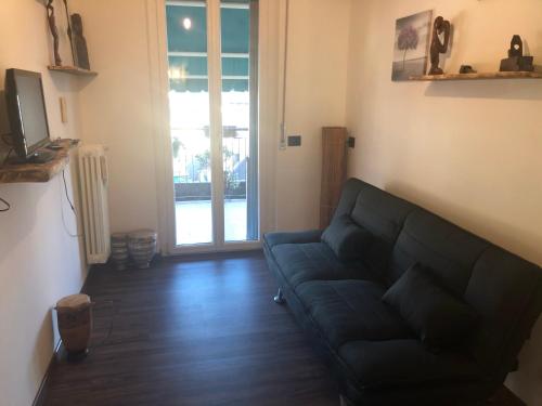 a living room with a black couch and a sliding glass door at ATTIC HOUSE - IL TUO ATTICO A RAPALLO in Rapallo