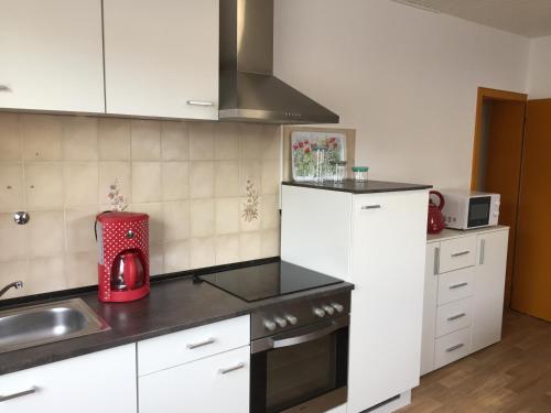 eine Küche mit weißen Schränken und einem roten Gerät in der Unterkunft Ferienwohnung Mimi Souterrainwohnung in Kastellaun