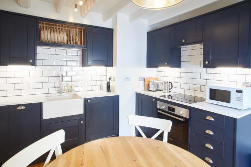 a kitchen with dark blue cabinets and a wooden table at Host & Stay - Gun Gutter House in Staithes