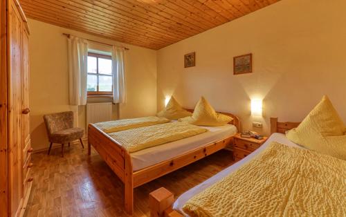 a bedroom with two beds and a chair and a window at Ferienwohnungen Weghofer F**** (Viechtach) in Viechtach