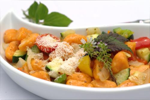 a white bowl of food with carrots and other vegetables at Gasthof Brandlhof in Wolfsegg am Hausruck