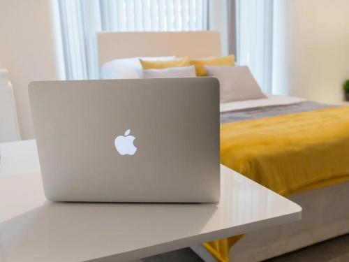 a laptop computer sitting on a white table next to a bed at TownHouse @166 Ruskin Rd in Crewe