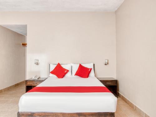 a bedroom with a large bed with red pillows at Capital O Hotel La Siesta, Gomez Palacio in Gómez Palacio