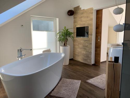 a bathroom with a white tub and a tv at Luxus-Ferienwohnung Saalhausen in Saalhausen
