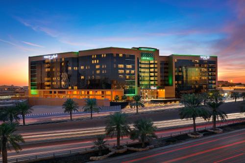 a large building with palm trees in front of a street at voco - Riyadh, an IHG Hotel in Riyadh