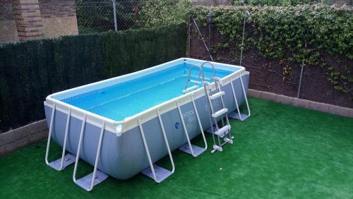 a small swimming pool on a green lawn at Los Alisos Casa Rural in Guadalix de la Sierra