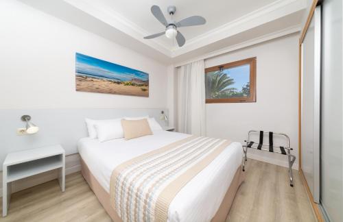 een witte slaapkamer met een bed en een plafondventilator bij Los Zocos Impressive Lanzarote in Costa Teguise