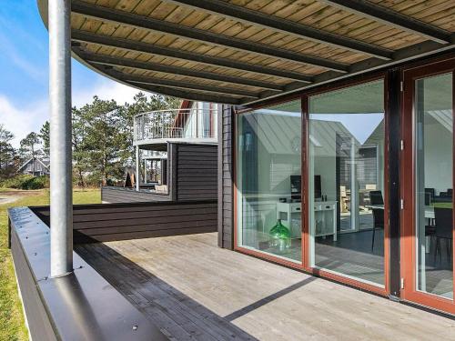 a house with glass doors and a deck with a table at 6 person holiday home in R m in Sønderby