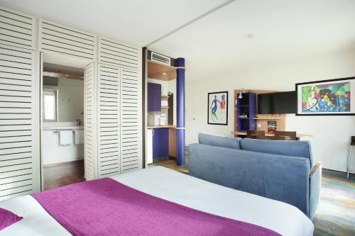 - une chambre avec un grand lit et une couverture violette dans l'établissement Suite-Home Orléans-Saran, à Saran