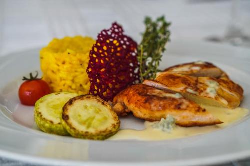 a plate of food with chicken and fruit on it at Grami Hotel in Bansko