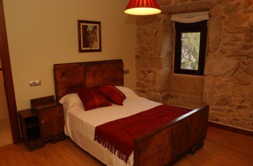 um quarto com uma cama e uma parede de pedra em CASA RURAL LAR DE VILARINO em Poio