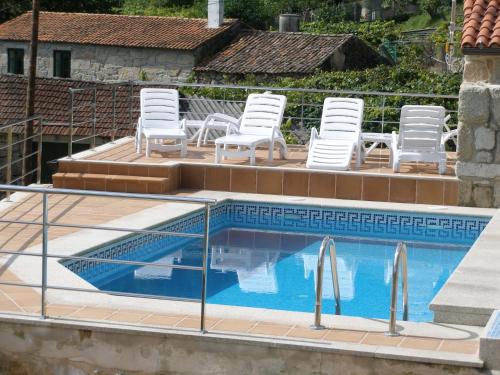 uma piscina com cadeiras brancas e um monte de móveis em CASA RURAL LAR DE VILARINO em Poio