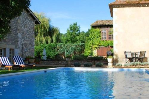 - une piscine dans une cour avec 2 chaises et une maison dans l'établissement Manoir du Bois Mignon Luxury Home - Dordogne, à Le Fleix