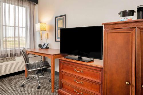 a hotel room with a desk and a television on a dresser at La Quinta by Wyndham Naples East (I-75) in Naples