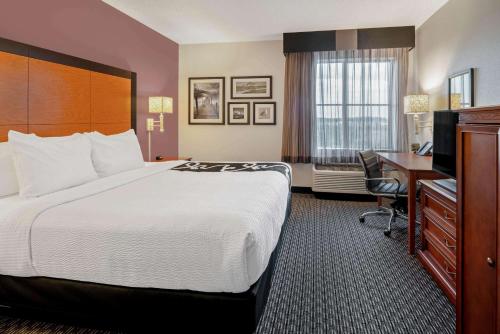 a hotel room with a large bed and a desk at La Quinta by Wyndham Naples East (I-75) in Naples