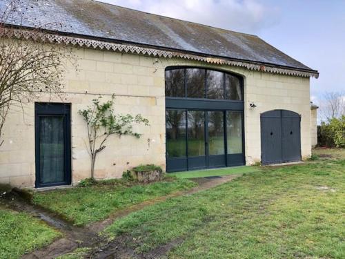 een wit gebouw met twee deuren en een grasveld bij Le Logis de la Tour Saint Jacques in Chouzé-sur-Loire