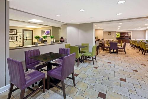 a restaurant with purple chairs and tables and a counter at La Quinta by Wyndham Miami Airport East in Miami