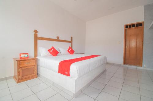 1 dormitorio con cama con almohadas rojas y puerta de madera en OYO Hotel Morelos, Villa Hidalgo, en Villa Hidalgo