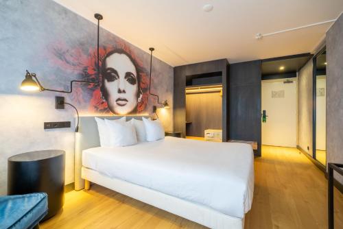 a bedroom with a large white bed with a painting on the wall at Skotel The Hague, Hotelschool The Hague in Scheveningen