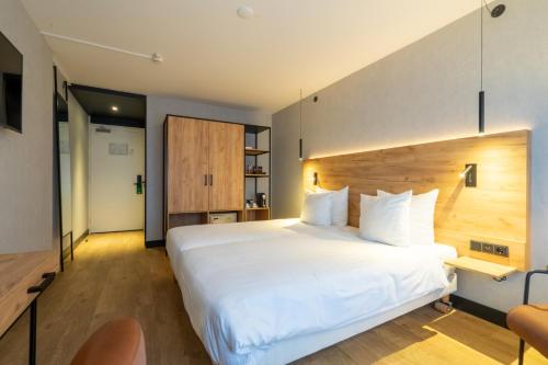 a bedroom with a large white bed and a chair at Skotel The Hague, Hotelschool The Hague in Scheveningen