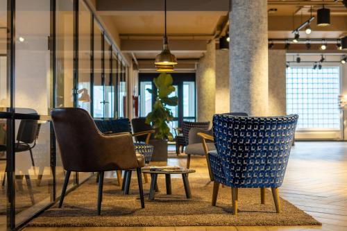 a group of chairs and tables in a room at Skotel The Hague, Hotelschool The Hague in Scheveningen