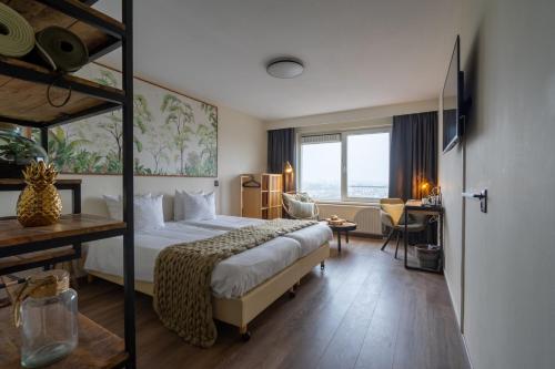 Cette chambre comprend un grand lit et un bureau. dans l'établissement Skotel The Hague, Hotelschool The Hague, à Scheveningen