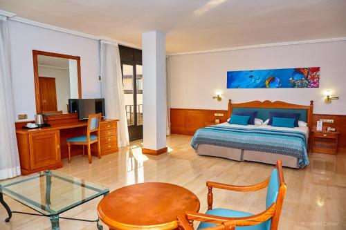 a bedroom with a bed and a desk and a table at Hotel Zentral Center - Adults only in Playa de las Americas