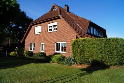 a red brick house with two windows and a hedge at Ferienwohnung Hooge Loogen, 35212 in Holtland
