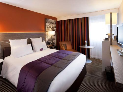 a hotel room with a large bed and a desk at Mercure Chambéry Centre in Chambéry