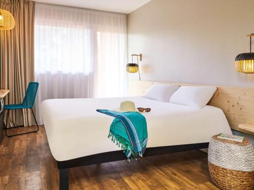 una habitación de hotel con una cama blanca con sombrero en ibis Thalassa Hyeres Plage, en Hyères