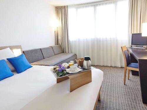 a hotel room with a large bed and a desk at Novotel Paris Rueil Malmaison in Rueil-Malmaison