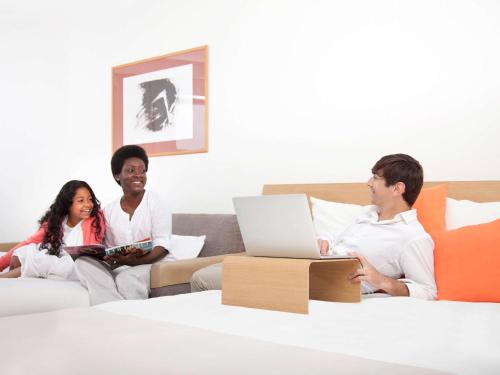 a group of people sitting on a couch with a laptop at Novotel Paris Rueil Malmaison in Rueil-Malmaison