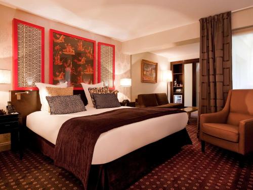 a hotel room with a large bed and a chair at Le Stendhal - Vendôme in Paris