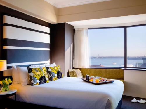 a hotel room with a bed, table and window at Mövenpick Hotel Auckland in Auckland