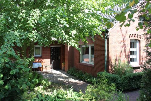 um edifício de tijolos vermelhos com uma porta e um quintal em Ferienwohnung Mientje, 35214 em Hesel