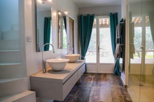 La salle de bains est pourvue de 2 lavabos et de rideaux verts. dans l'établissement Luxueux Mas provencal immérgé dans la nature, au Castellet
