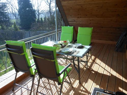 una mesa y cuatro sillas verdes en una terraza en Ferienwohnung An der Eichenallee, 35200, en Hesel