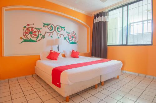 een slaapkamer met oranje muren en een bed met rode kussens bij OYO Hotel Casino Del Valle, Matehuala in Matehuala
