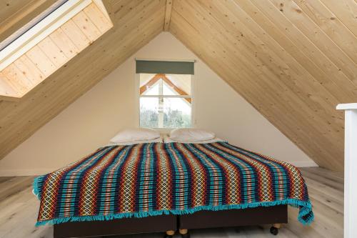 een bed met een kleurrijke deken op een zolder bij Appartementen Parkzicht in Bergen aan Zee