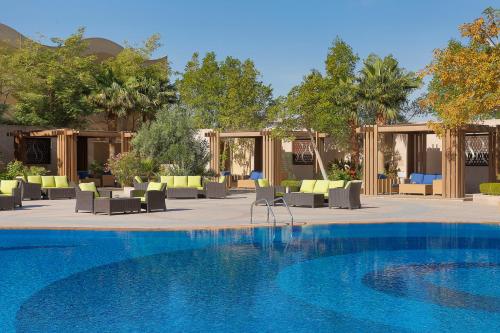 a large swimming pool with chairs and tables at Voco - Riyadh by IHG in Riyadh