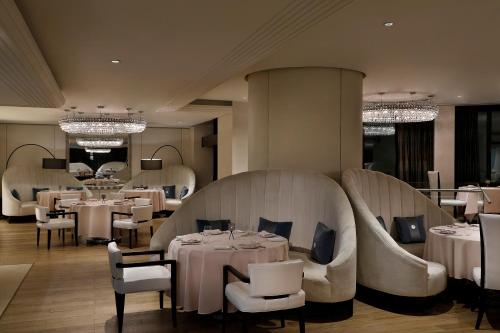 a restaurant with white tables and chairs and chandeliers at Voco - Riyadh by IHG in Riyadh