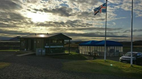 a building with a flag and a car parked next to it at Hlíd Huts in Myvatn