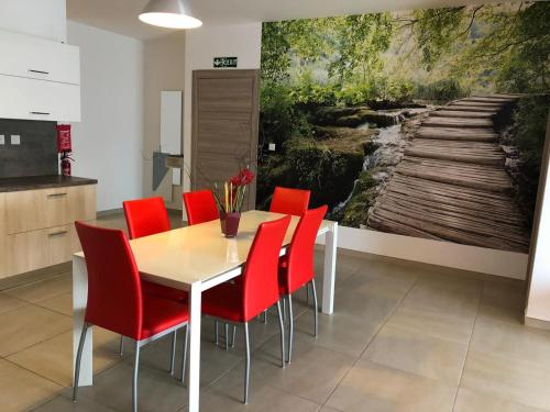 a dining room with a table and red chairs at 189 Chezli Court in Birżebbuġa